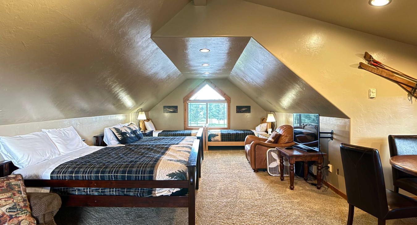 This massive loft over the garage serves as a private apartment, fully equipped with multiple beds, a TV area, and private dining space.
