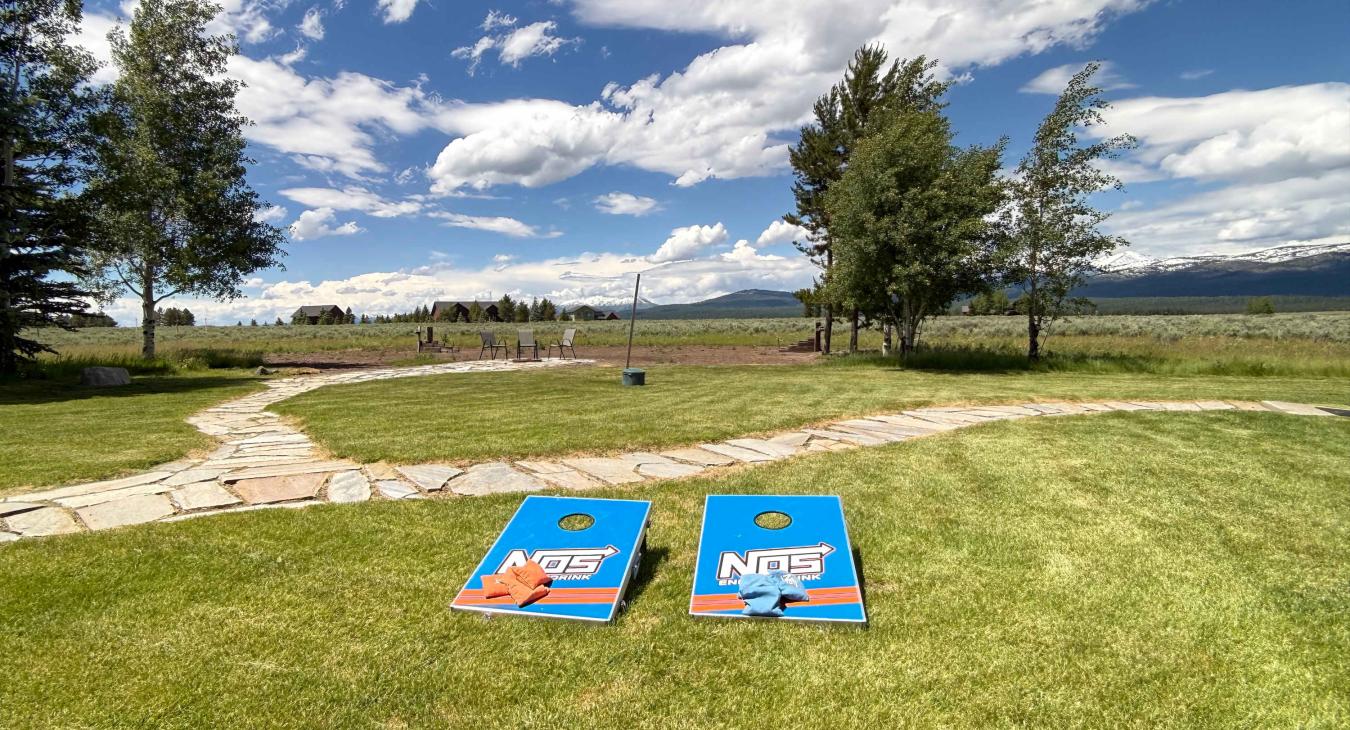Have some outdoor fun with a game of cornhole on the spacious, manicured lawn under the beautiful blue sky.