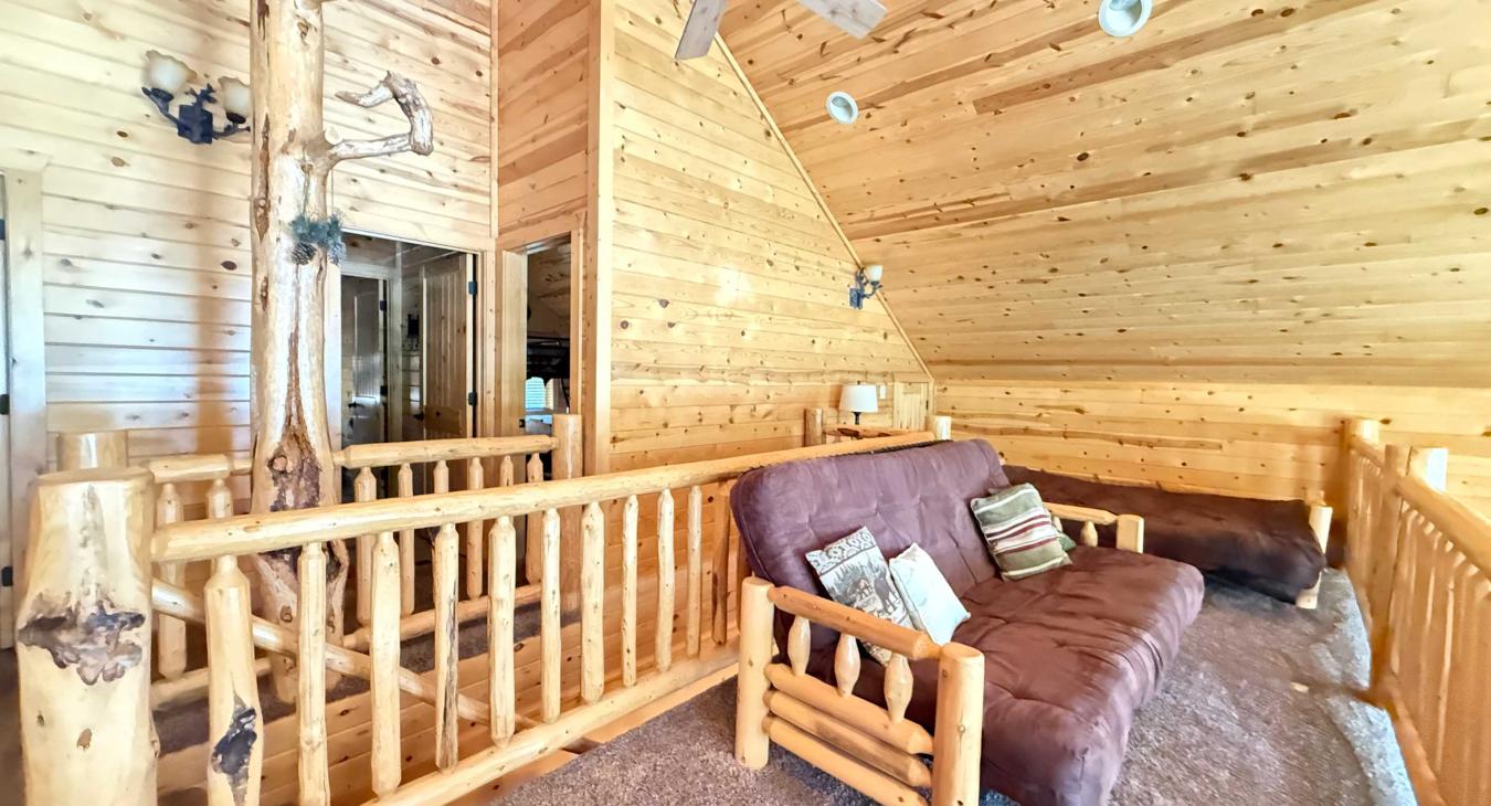 The open upstairs loft offers a versatile bonus space, featuring two comfortable futon sofas that easily convert into additional beds.