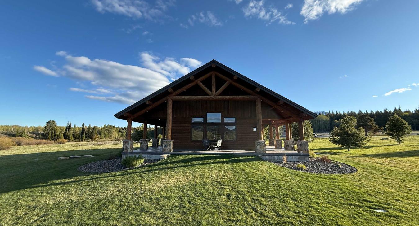 Lots of open grass surrounding the cabin.