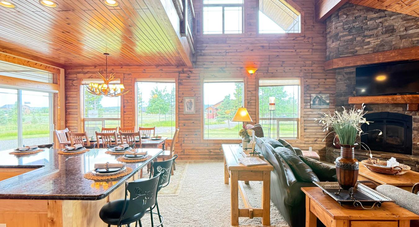 Floor-to-ceiling windows flood the living and dining spaces with natural light, offering beautiful views of the surrounding nature.