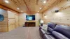 Along one wall, a large, plush couch is positioned facing the television, creating a perfect spot to unwind after a day of outdoor adventures or to catch a game or movie with friends.