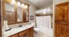 Basement shared bathroom with shower tub combo, toilet, and sink vanity.