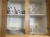 Kitchen is equipped with cups, wine glasses, and plates.