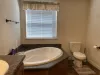 Master bathroom with soaking tub, standing shower, toilet, and double sink vanity.