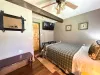 This warm guest room includes a wall-mounted flat-screen TV, rustic wall art, and a beautiful live-edge wooden bench at the entrance.