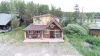 A bird's-eye view highlights the cabin's stunning architecture, expansive front deck, and peaceful location nestled among lush evergreen trees.