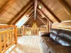 The open upstairs loft area features a comfortable leather sofa nestled under striking log A-frame ceilings, offering a cozy spot to relax.