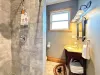 The pristine 3/4 bathroom features a tiled walk-in shower, a beautiful dark wood vanity with a granite top, and bright vanity lighting.