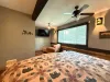The spacious master suite also offers a private wall-mounted TV and a cozy leather armchair with an ottoman, perfect for a quiet reading escape.